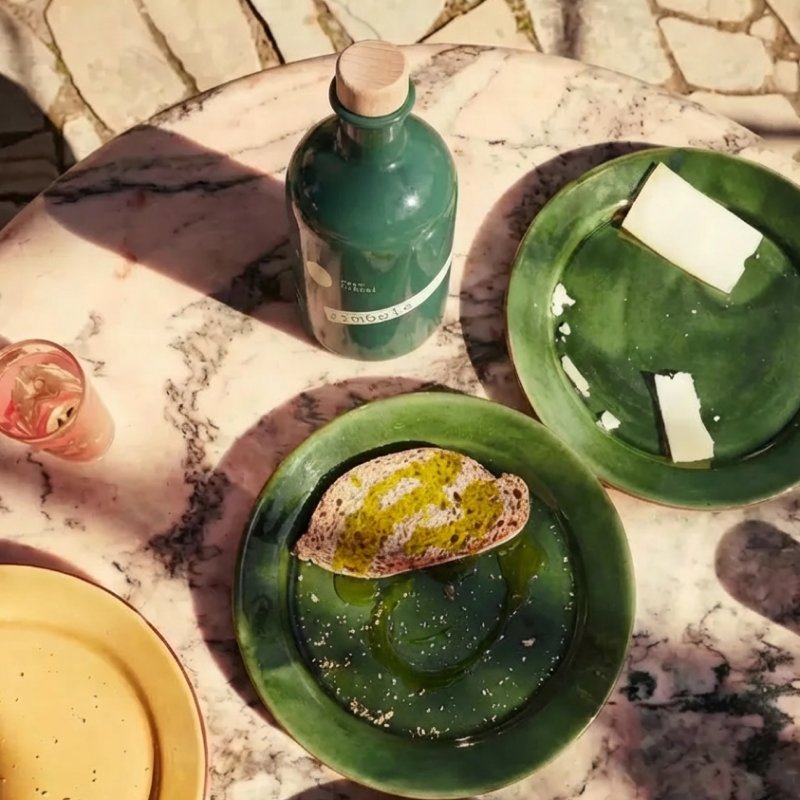 Platos con pan y aceite de oliva virgen extra junto a la botella Símbolo